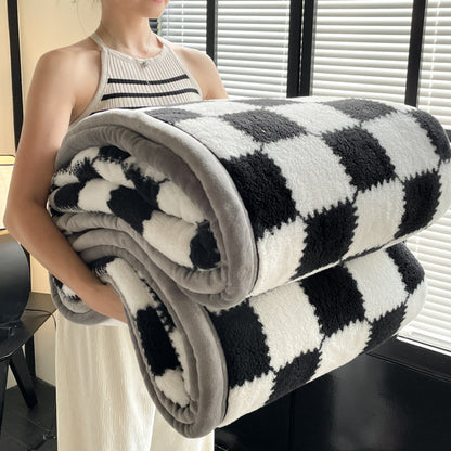 Person holding a black and white checkered blanket indoors.