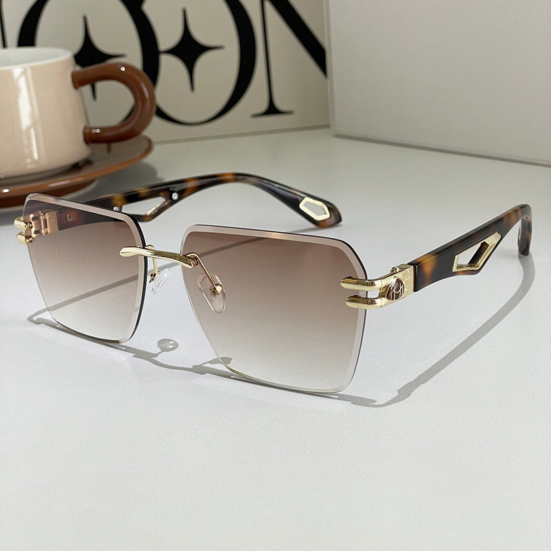 Sunglasses with tortoiseshell and gold frame on a light surface.