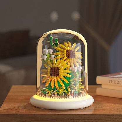 Decorative lamp with sunflowers inside a glass dome on a wooden surface.