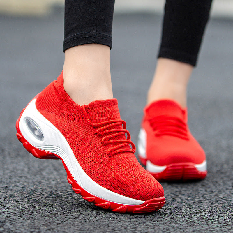Red athletic shoes with white soles on a blurred pavement background