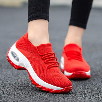 Red athletic shoes with white soles on a blurred pavement background