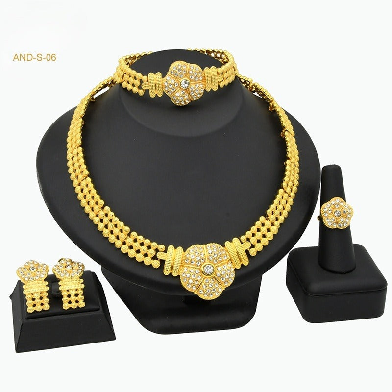 Gold necklace set with matching bracelet, earrings, and ring on a black stand.