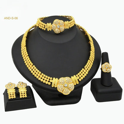 Gold necklace set with matching bracelet, earrings, and ring on a black stand.