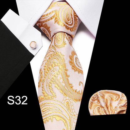 Gold paisley tie set with pocket square and cufflinks on a black background