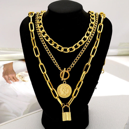 Layered gold-tone chain necklace set with circular medallion and padlock charms
