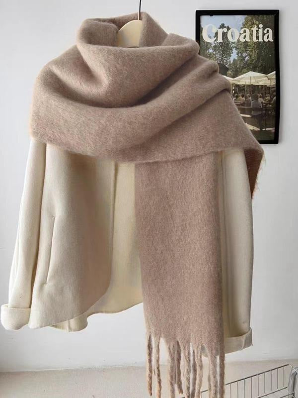 Beige scarf with fringe draped over a mannequin against a white wall.