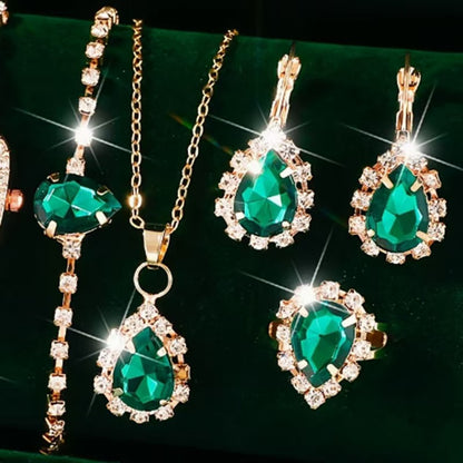 Jewelry set with emerald green teardrop pendants on a dark background