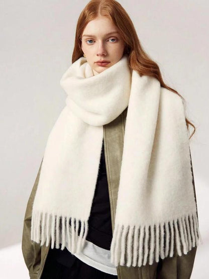 Woman wearing a white scarf with fringes on a plain background
