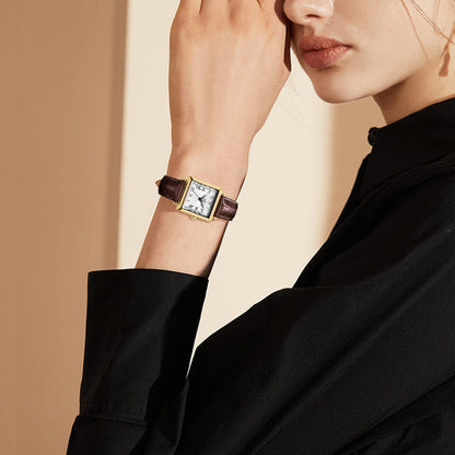 Retro square watch on wrist with brown leather strap and gold-tone case.
