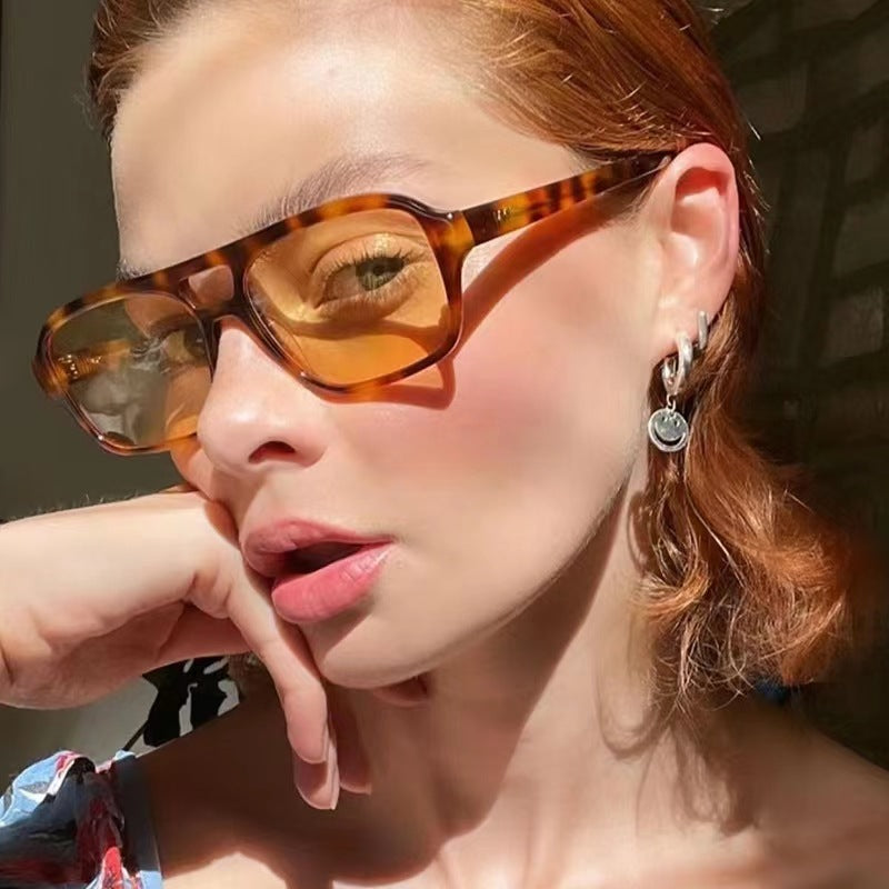Close-up of a person wearing tortoiseshell sunglasses with a blurred background