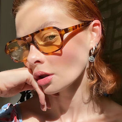 Close-up of a person wearing tortoiseshell sunglasses with a blurred background