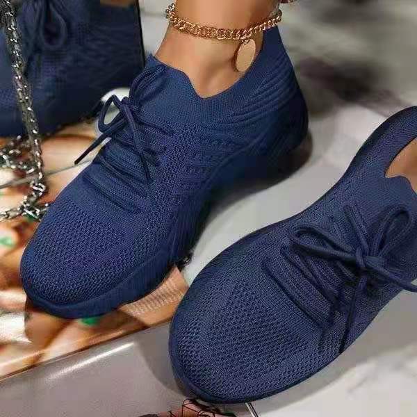 Blue sneakers worn by a person on a reflective surface
