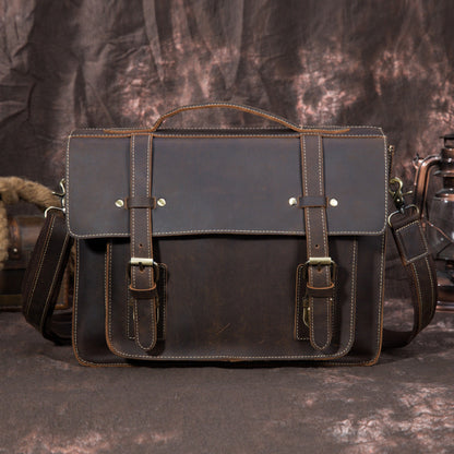 Brown leather satchel bag with straps on a textured dark background