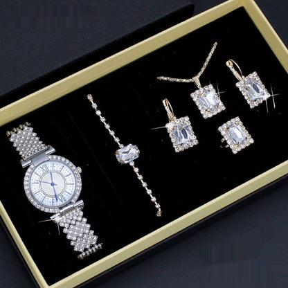 Jewelry set including a watch and earrings on a black display box with gold trim.