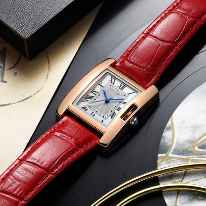 Luxury watch with red leather strap on a decorative surface