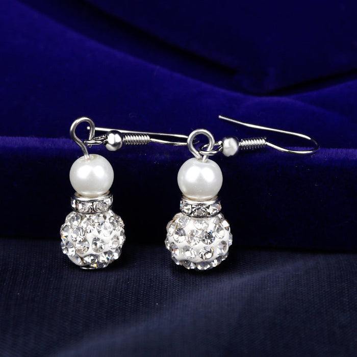 Pearl and crystal earrings on a dark blue fabric background