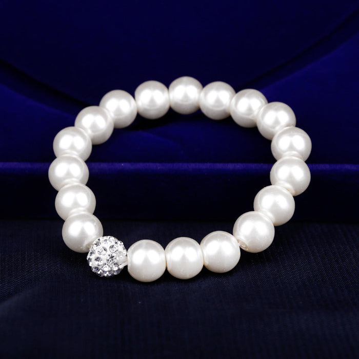 Pearl bracelet with a crystal clasp on a dark blue fabric background