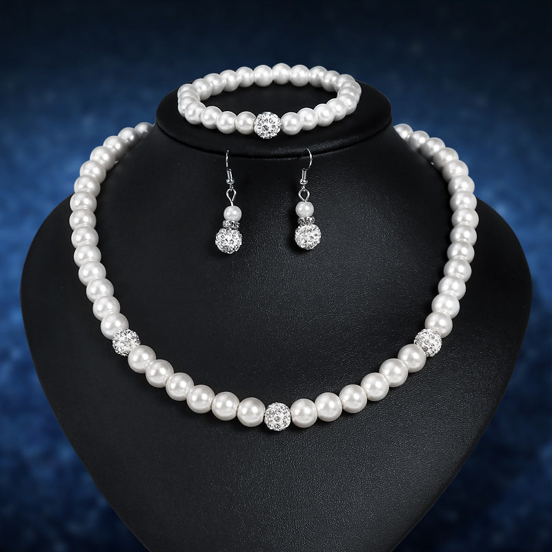 Pearl jewelry set with necklace, bracelet, and earrings on a black stand against a dark blue background.