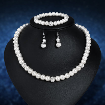 Pearl jewelry set with necklace, bracelet, and earrings on a black stand against a dark blue background.
