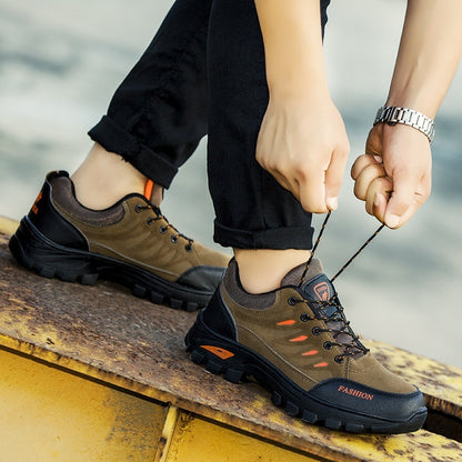 Person wearing brown hiking shoes with black soles, tying a shoelace on a blurred background.