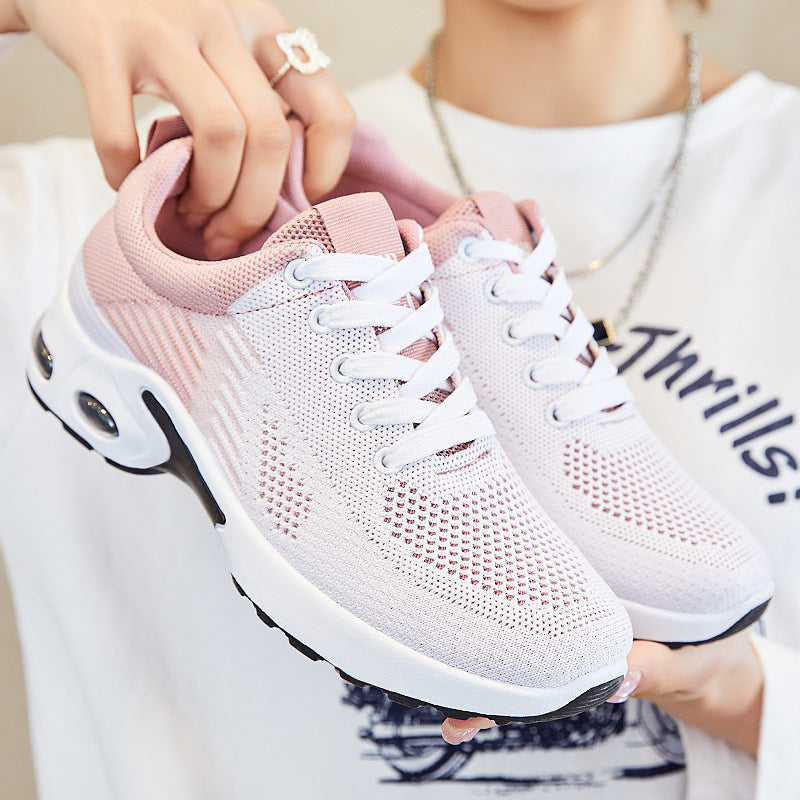 Pink and gray athletic shoes with white soles being held by a person.