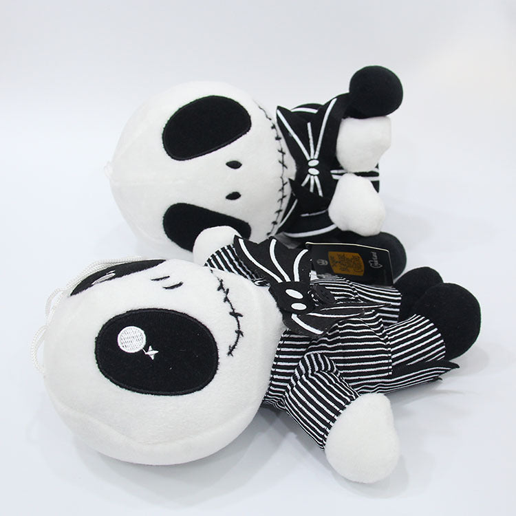 Black and white plush toy with striped pants on a white background