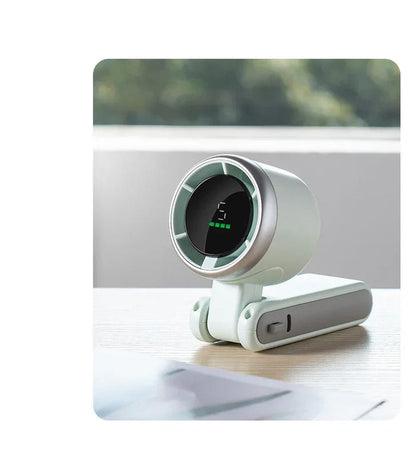 Light green foldable mini desktop fan resting on desk, circular grille