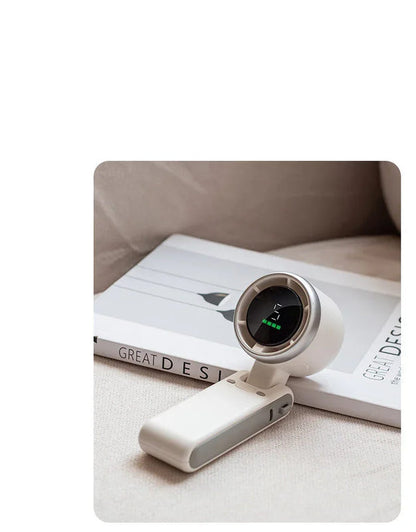 White foldable mini desktop fan with display window, placed on book stack