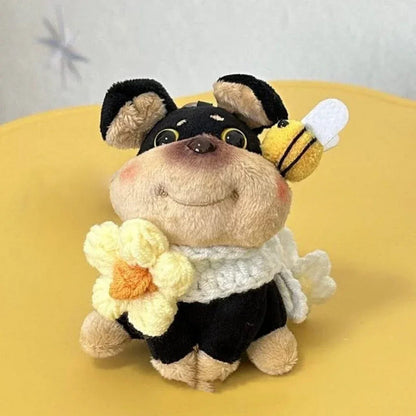 Puppy plush keychain with black outfit, white scarf, and yellow flower detail