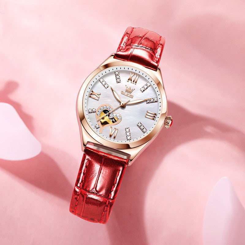 Luxury watch with red strap and gold casing on a pink background