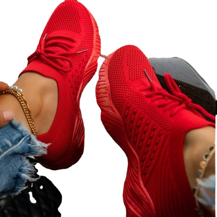 Red sneakers worn with denim jeans on a white background