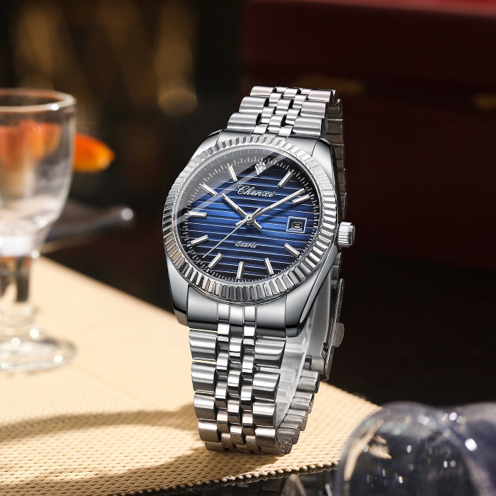 Silver watch with blue face on a table with a blurred background