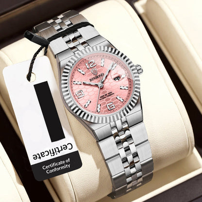 Silver watch with pink face on a white cushion, accompanied by a tag displaying a retail price.
