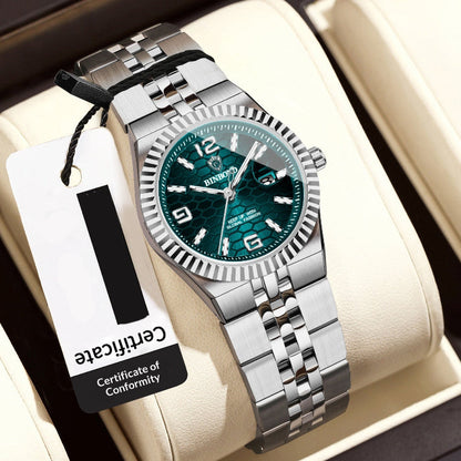 Silver women's watch with green dial on a white cushion, accompanied by a price tag.