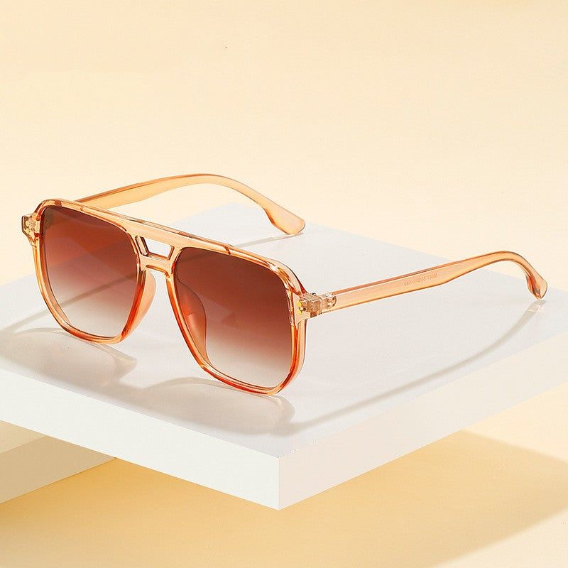Sunglasses with orange frame and brown lenses on a white platform with a yellow background