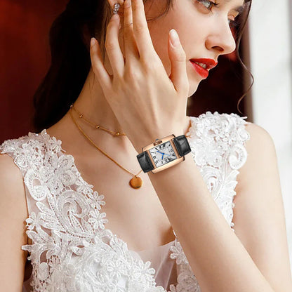 Woman wearing a rose gold watch with a black strap and white lace top.