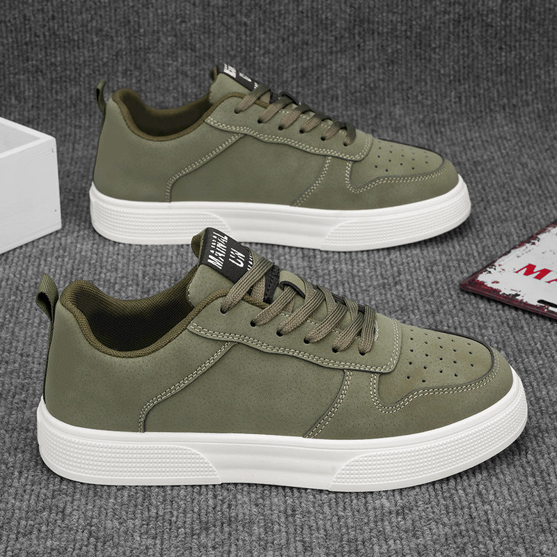Pair of green sneakers with white soles on a gray surface