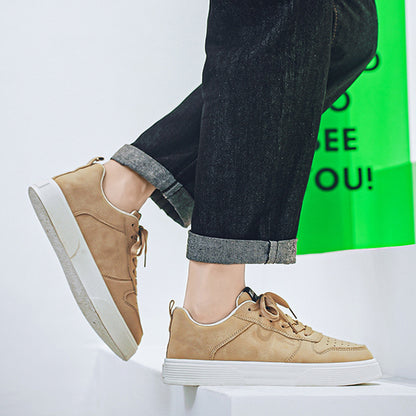 Tan sneakers worn with dark jeans on a white background