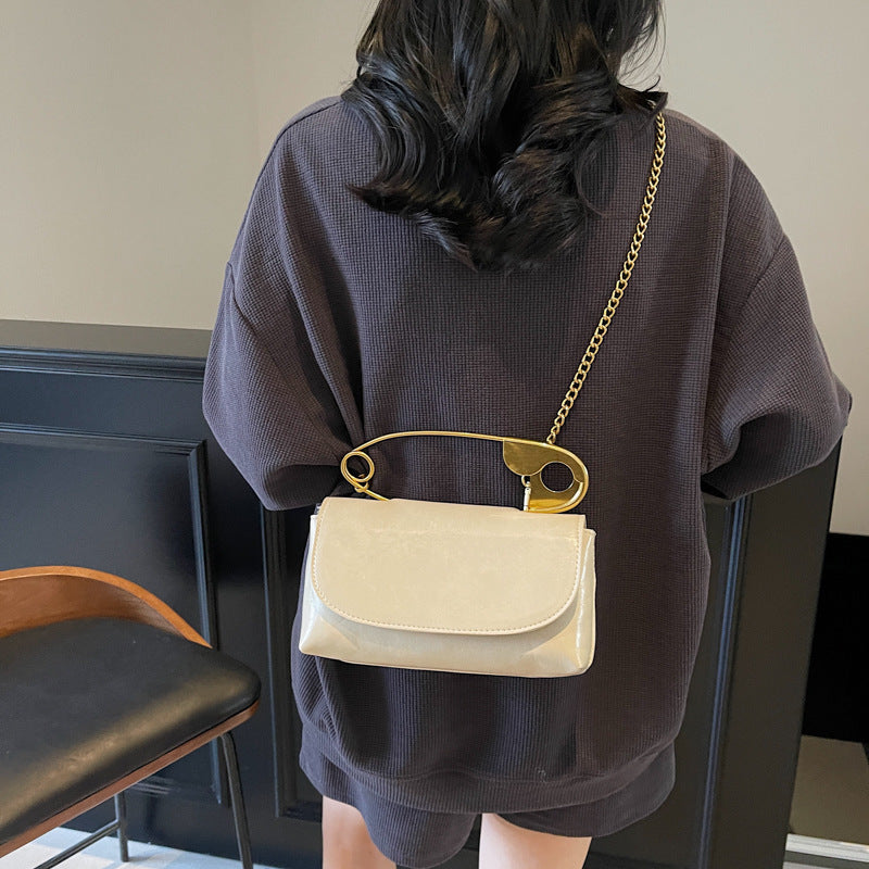 Person wearing a beige handbag with a gold chain strap in an indoor setting