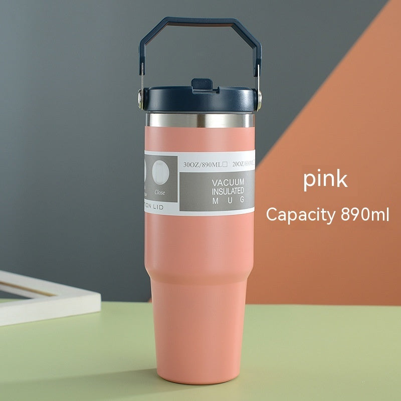 Pink vacuum insulated mug with a gray label on a green surface.