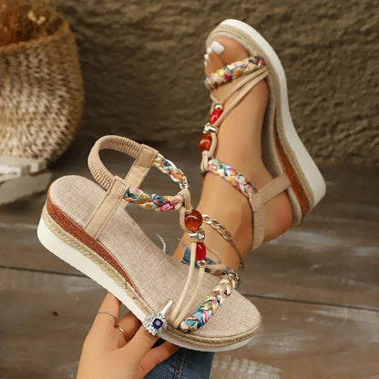 Apricot wedge sandals with braided straps, red bead drop, and crisscross ankle design.