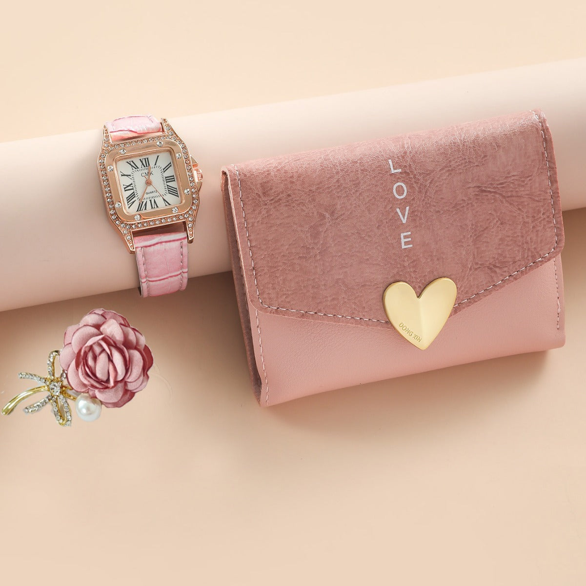 Pink watch, wallet, and flower on a beige background