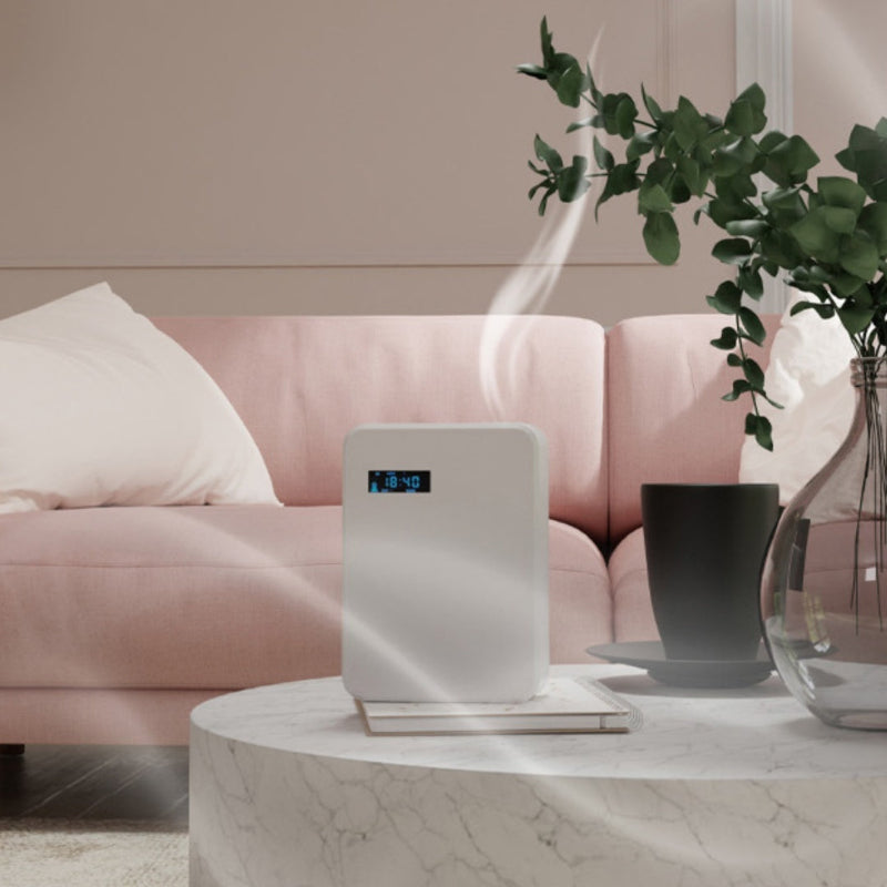 Air purifier on a marble table with a pink sofa and plant in the background