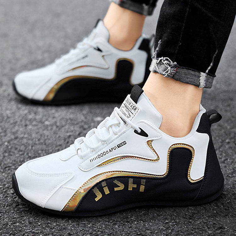 White and black sneakers with gold accents worn by a person on a gray surface