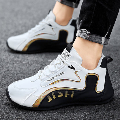 White and black sneakers with gold accents worn by a person on a gray surface