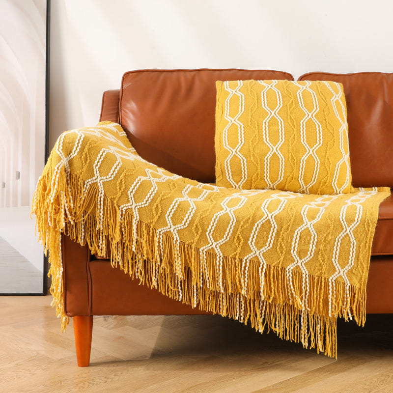 Mustard yellow knitted throw blanket with white lattice pattern and fringe tassels