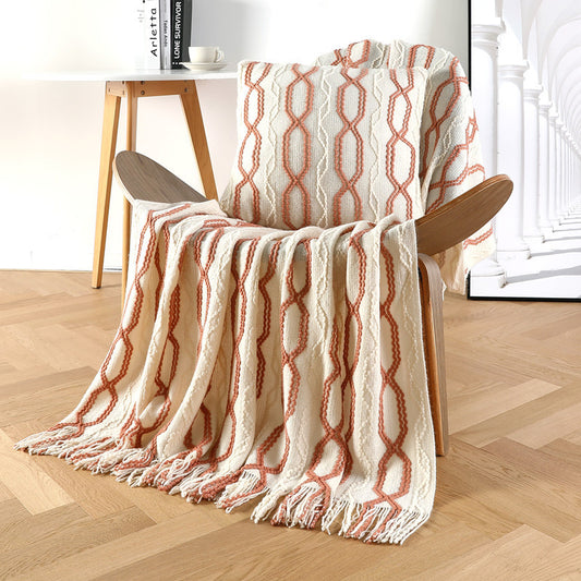 Beige sofa throw blanket with orange and white diamond knit pattern and fringe tassels