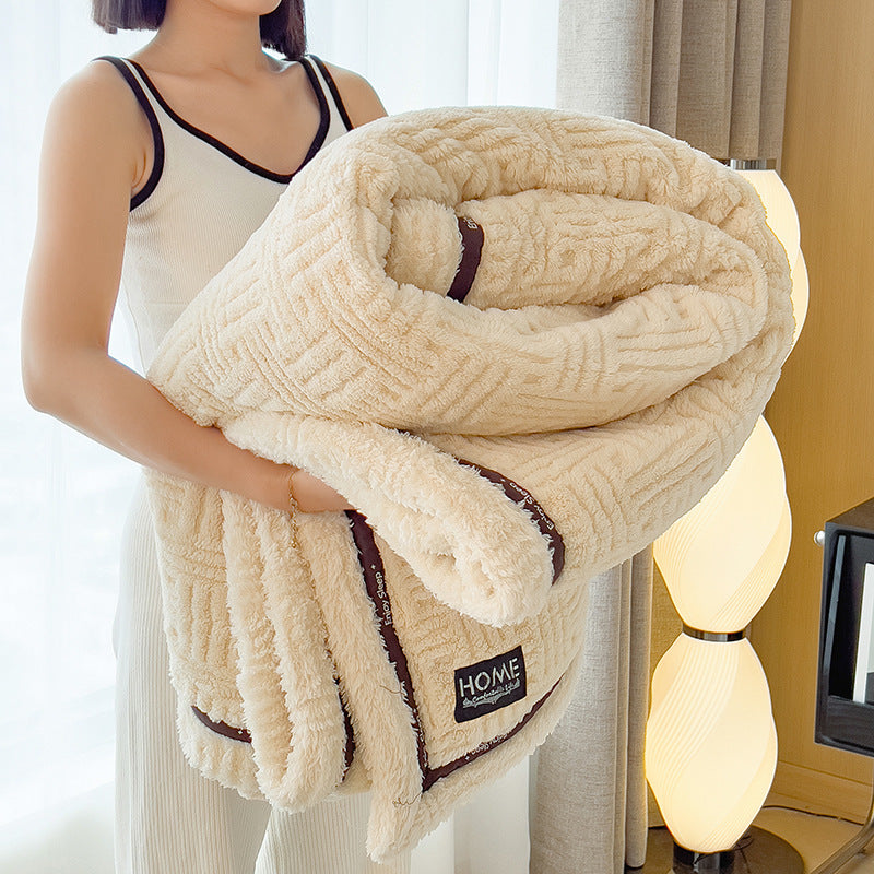 Light beige plush velvet throw blanket with textured weave, dark edge stripe, and label patch