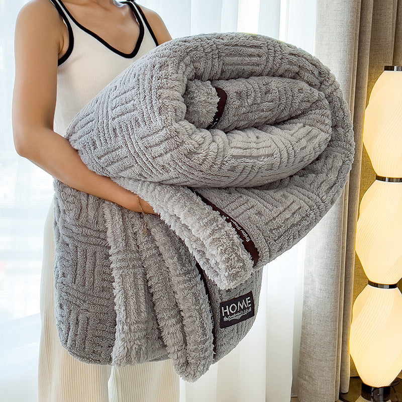 Person holding a textured gray blanket with 'HOME' label in a room setting.