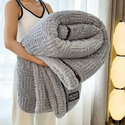 Person holding a textured gray blanket with 'HOME' label in a room setting.